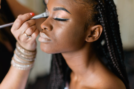 Make up of american black model. Preparing to shooting. Closed eyes. Braiding