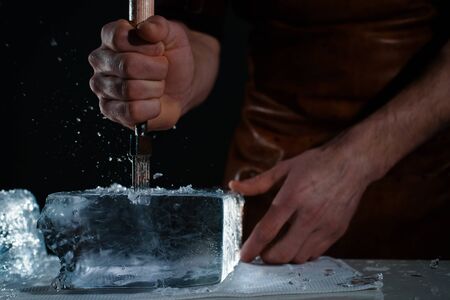 Barman chopping ice using a special knife. ?hunks of ice flying aroundの写真素材