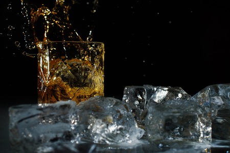 whiskey splashing in a glass. Ice aroundの写真素材