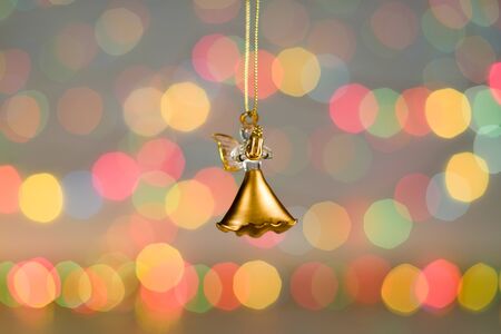 Christmas decorations. Close up photo of New Year small golden angel . Nice toy in colorful lightの写真素材