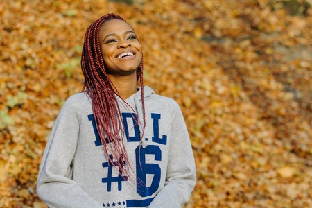 Autumn outdoor portrait of beautiful African American young woman smiling in park. Black peopleの写真素材