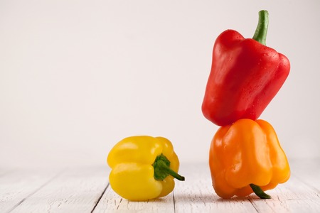 Three juicy bellpeppers on wooden table in studioの写真素材