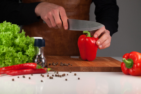 Man cutting red big peeper on the wooden cutting boardの写真素材