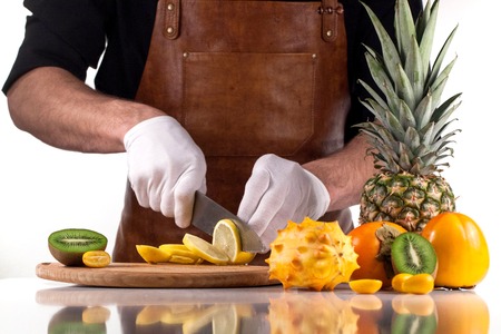 Cutting lemon into slices. Chef in white gloves. Assorted fruitsの写真素材