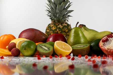 Juicy tropical fruits with water drops on a white surface. Great reflection of fruitsの写真素材