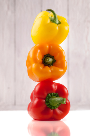 Three juicy sweet peppers laying on each other on wooden backgroundの写真素材