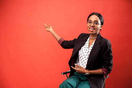 Smiled african american women showing something on a red background.の写真素材