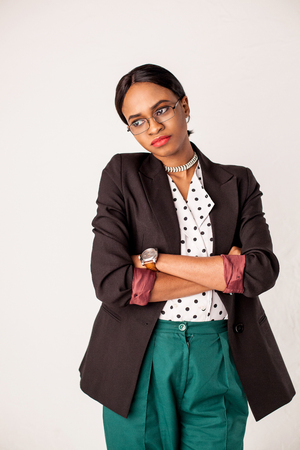 Pretty businesswoman with shiny dark skin standing on the white background with her hands crossed.の写真素材