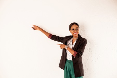 Smiled african american girl saying something and standing at the white wall.の写真素材