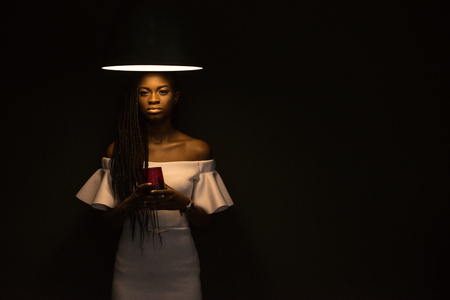 Pretty african american girl standing under the chandelier on the dark beckground.の写真素材