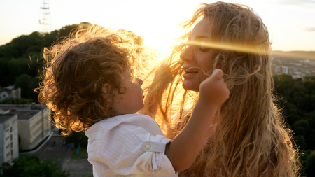 Pretty mother with her little son. Sunset. Little boy playing with mothers hair.の写真素材