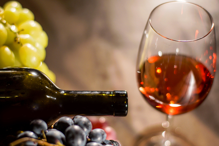 Close-up shot of wine glass ans wine bottle. Big colourful grapes around wine bottle.の写真素材
