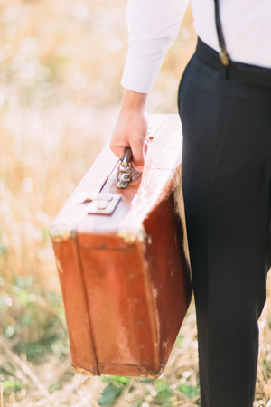 The vintage suitcase is being held by the hands of the groomの写真素材