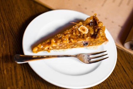 The close-up view of the piece of the honey cake covered with bananas and nutsの写真素材
