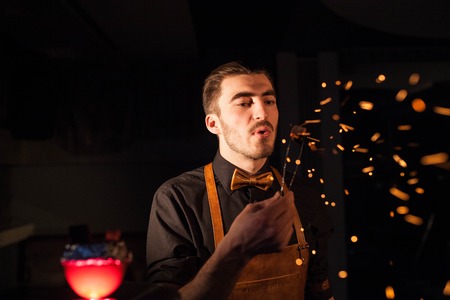 Handsome shisha man blowing on a hookah ember. Sparks flying in the air.の写真素材