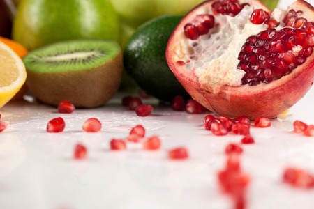 Close-up shot of pomegranate fruit in front of some other tropical fruits.の写真素材