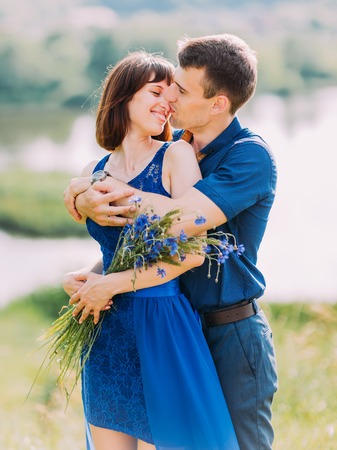 The close-up emotional portrait of the groom hugging the smiling girl back and kissing in the nose.の写真素材