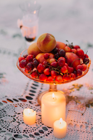 The close-up view of the shining candles near the cherries and peaches on the plate.の写真素材