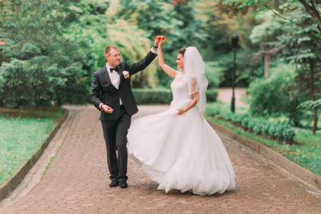 The horizontal view of the dancing newlyweds in the green park.の写真素材