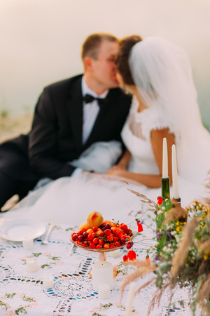 The wedding picnic at the blurred background of the kissing newlyweds near the sea.の写真素材