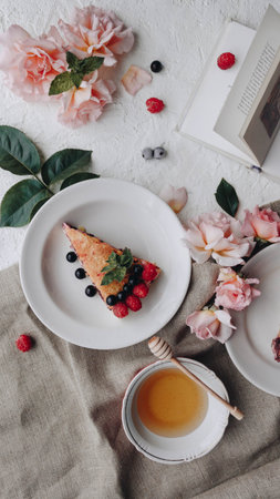 Delicious composition of the breakfast. Fruit pie with cup of tea and book placed on the table...