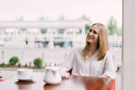 Close-up portrait of the beautiful smiling blond woman sitting in the cafe.の写真素材