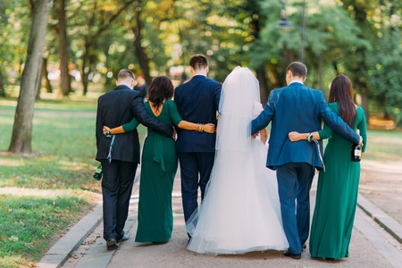 The back view of the newlyweds and their frined walking in the park.の写真素材