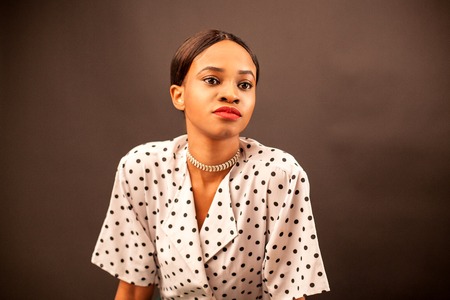 Portrait of attractive african american woman in white blouse and with red lips. Brown background.の写真素材