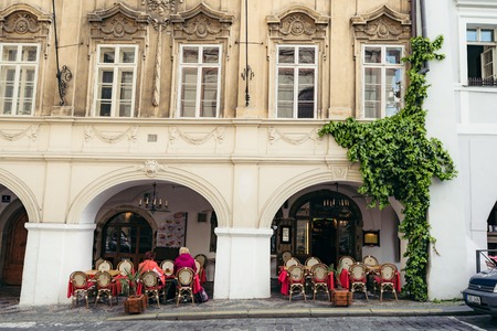 Lovely old street cafe full of people. The building is overgrown with plants. Prague location.の写真素材