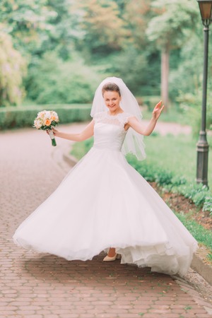 The emotional photo of the bride spinning round in the park.の写真素材