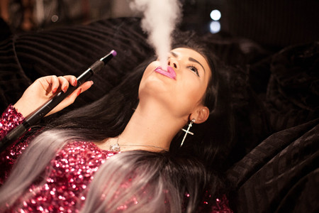 Pretty woman with nice makeup and hairstyle exhaling hookah smoke.の写真素材