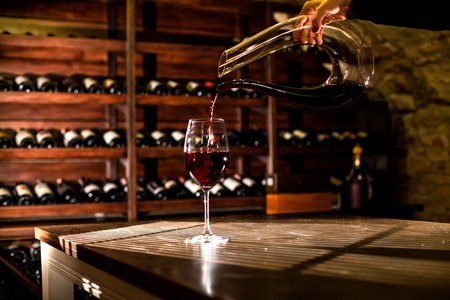 WIne pouring into a glaas placed on the table in a wine vault.の写真素材