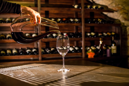 Hand holding figured glaas of wine. Empty glass on the table.の写真素材