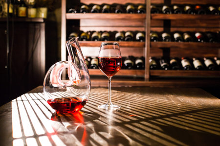 Wine carafe and wine glass on a wine shelves background.の写真素材