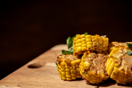 Grilled corn with herbs placed on a wooden tableの写真素材
