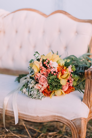 The minimalism composition of the colourful bouquet of flowers consisted ot the pink roses lying on the white stylish sofa.の写真素材