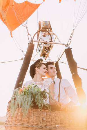 The upside view of the newlyweds in the airballoon basket looking at the right side. The bride is holding the wedding bouquet.の写真素材