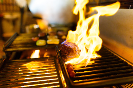 The spiced raw meat is grilling on the brazier with the burning wood in the kitchen of the restaurantの写真素材