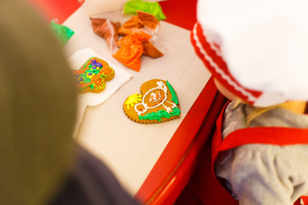 The lovely cookie in the form of the heart is decorated with green and yellow cream placed on the...