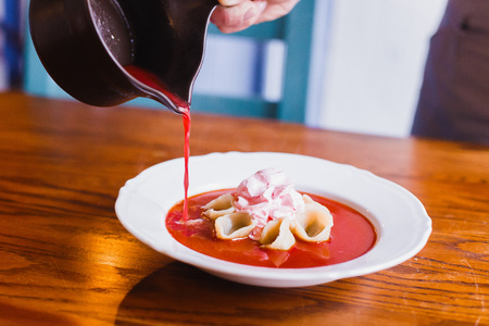 The waitress is pouring the borsch into the plate with dumplings. The close-up side viewの写真素材