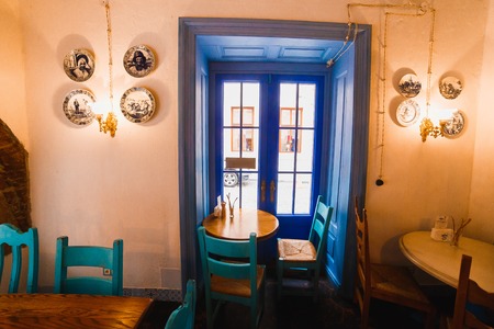 The horizontal photo of the bright chairs with table standing next to the blue door in the romantic vintage cafeの写真素材