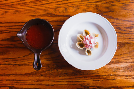 The composition of the plate with dumplings covered with pink sour cream and borsch in the panの写真素材