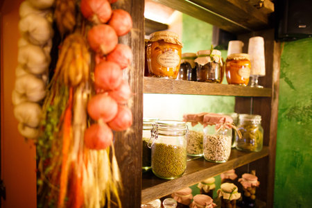 The side photo of the jars with spices placed on the wooden wardrobe and decorated with hanging...