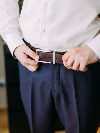 The hands of the groom are correcting the leather beltの写真素材
