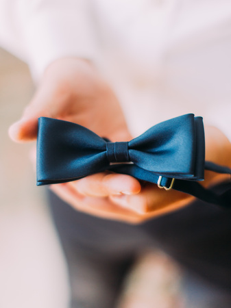 The stylish blue bow-tie in the hands of the groomの写真素材