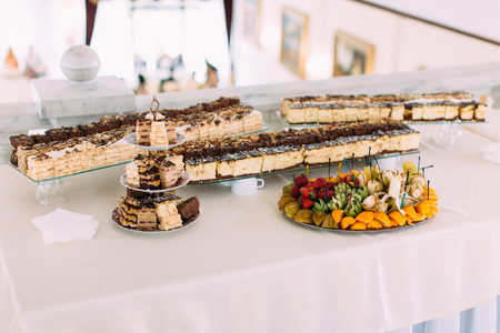 The wedding table full of different cakes and fruit plateの写真素材