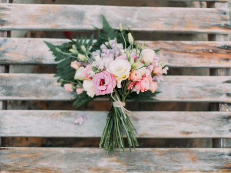 The horizontal portrait of the lovely wedding bouquet of colourful roses placed on the wooden backgroundの写真素材