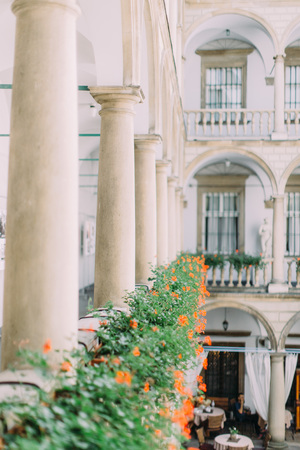 Vertical view of the ancient balcony full of orange flowersの写真素材