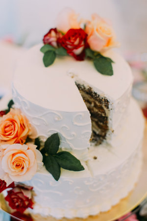 Colourful roses decorate the white wedding cake