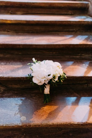 Close-up view of the beauitful white wedding bouquet laying on the wooden stairsの写真素材